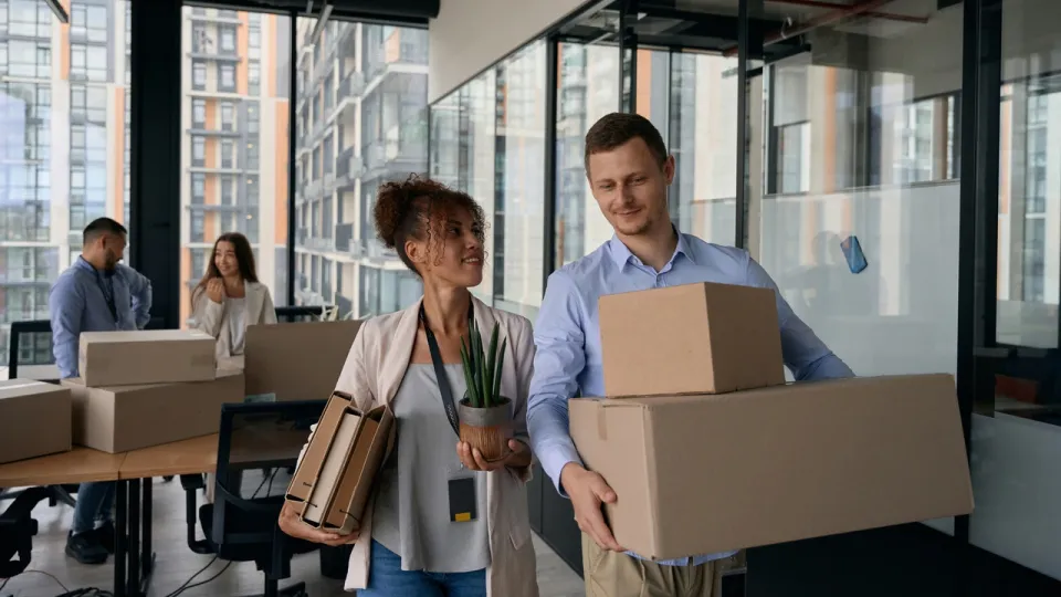 Colleagues carrying boxes and equipment during an office move