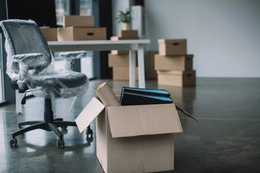 An office chair wrapped for protection beside a box of files